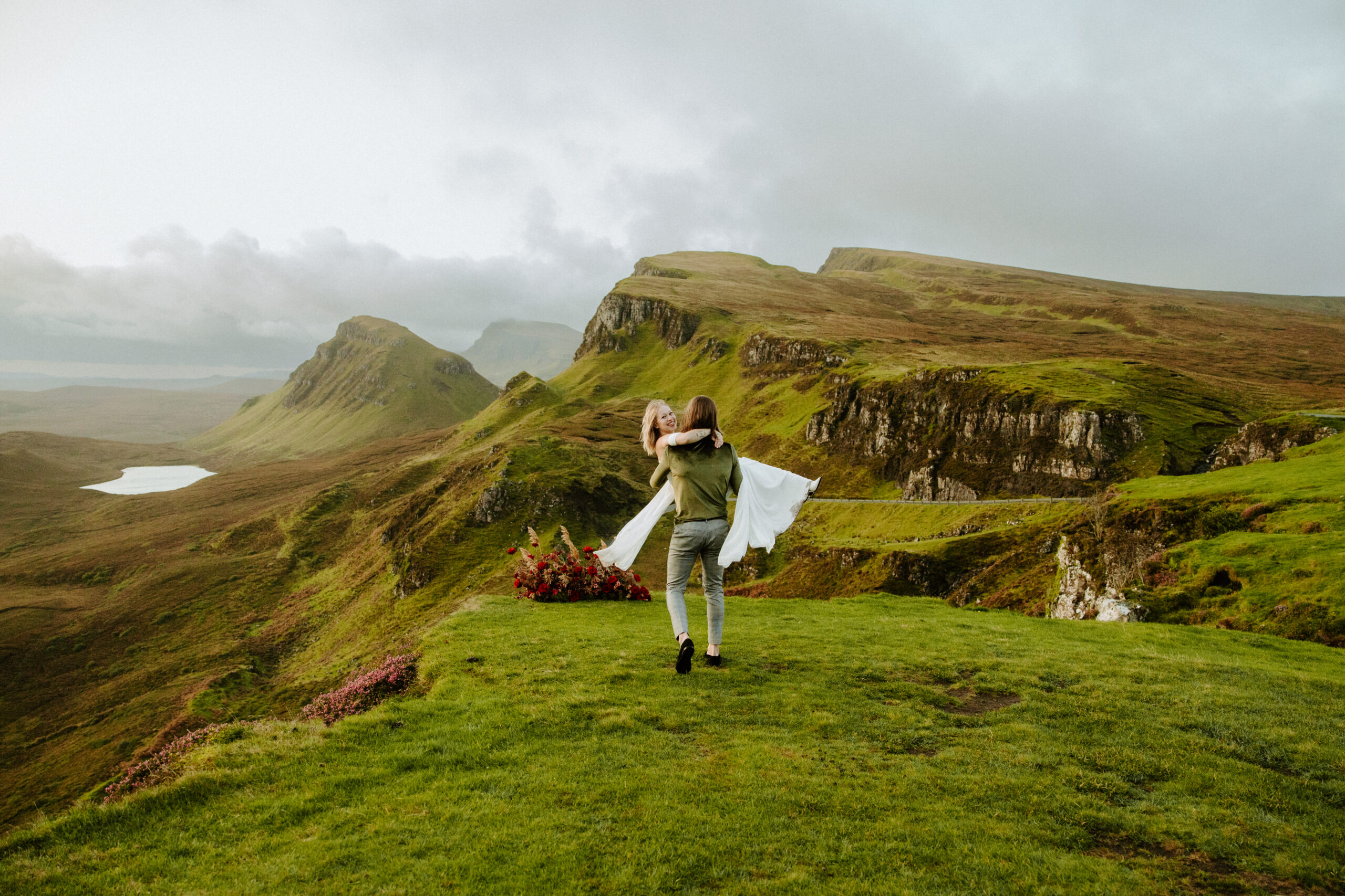 A joyful moment as the groom carries his bride away, her laughter echoing against the stunning backdrop of Scotland's rugged landscape, symbolizing the start of their new adventure together.