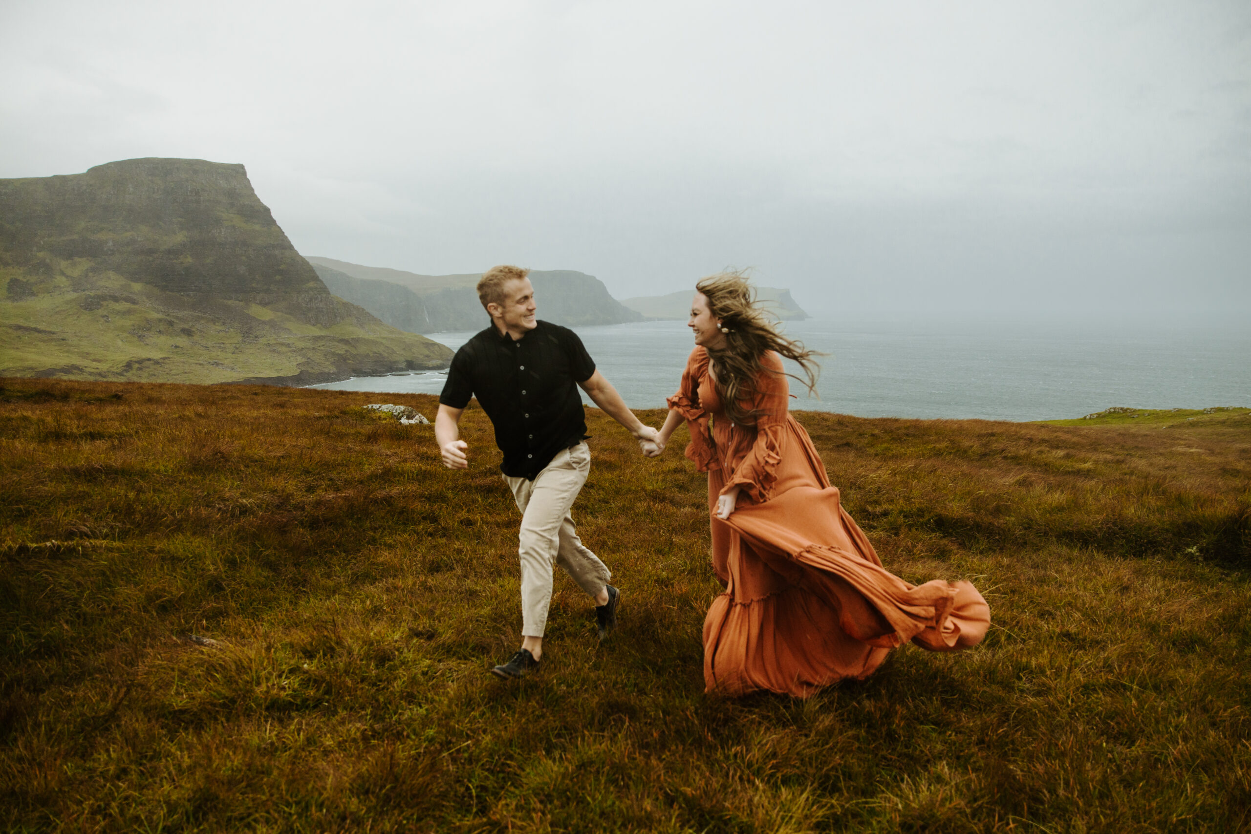 Couple standing together at Neist Point, with the dramatic cliffs and iconic lighthouse in the background during their Scotland elopement