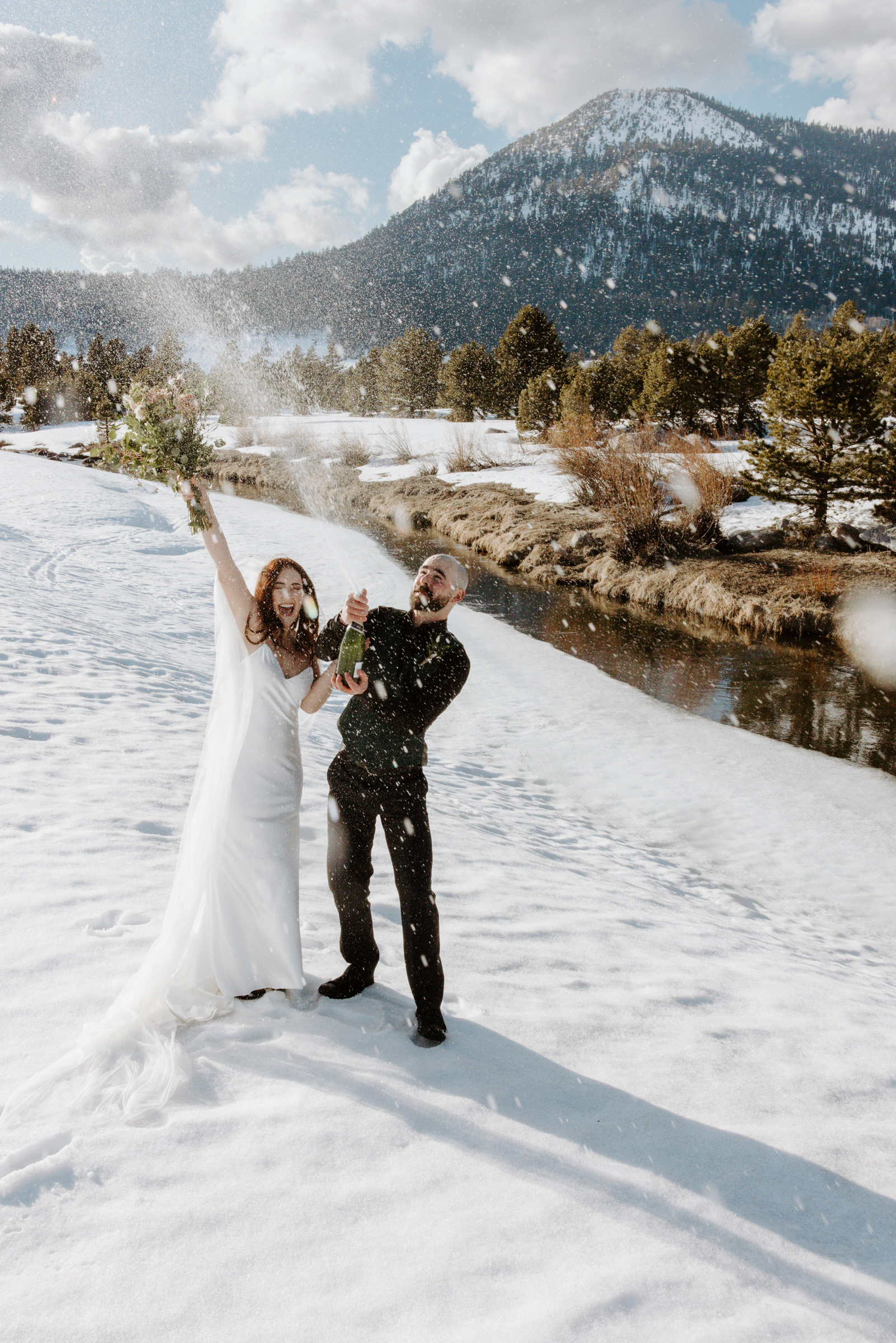 couple spraying champagne after they tied the knot in lake tahoe meadow in winter