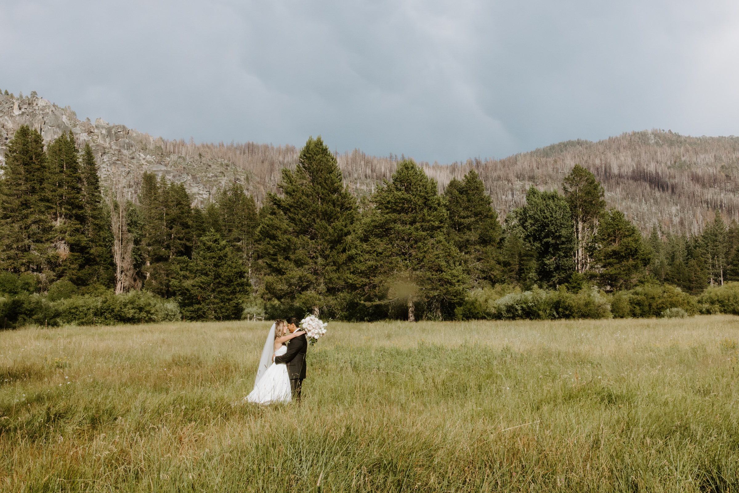 couple kissing in meadow after intimate wedding