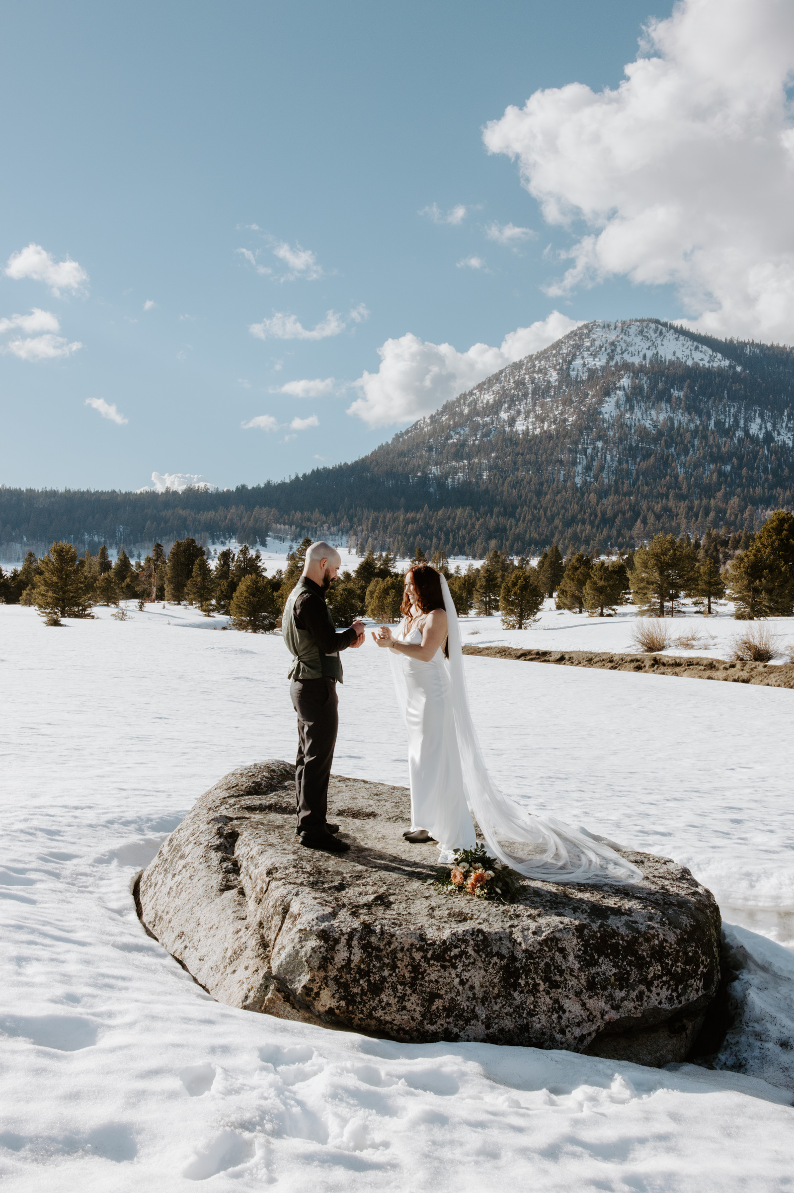 couple exchanging vows at winter elopement with tall peaks behind them