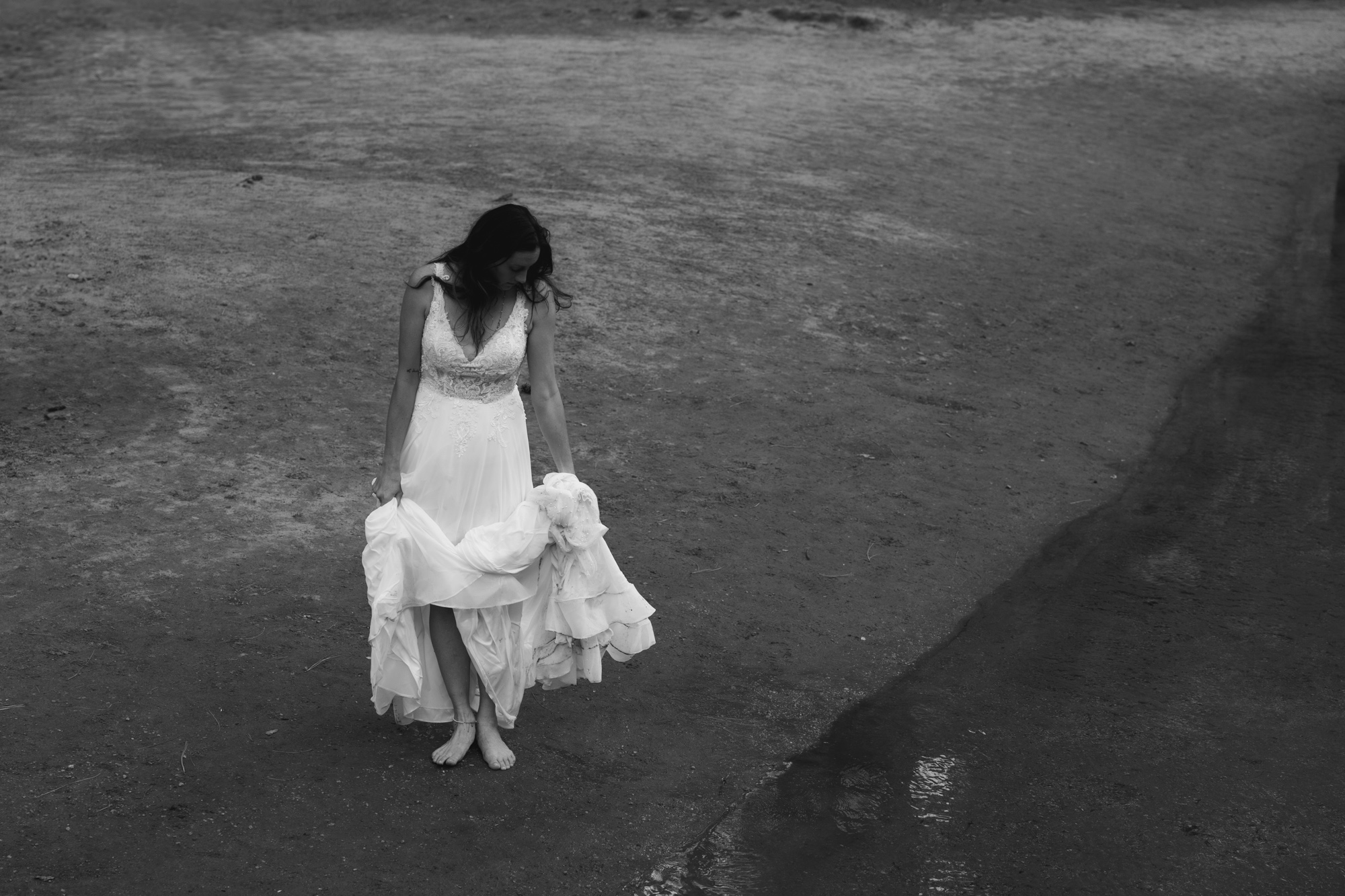 Bride standing in the river at Yosemite, surrounded by lush greenery and towering trees